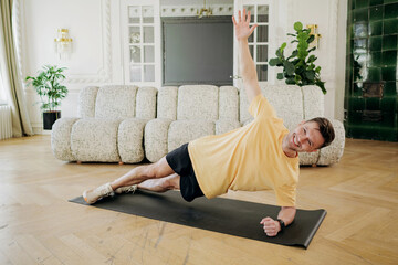 Man demonstrates a perfect side plank, challenging his core and balance in an airy and elegantly...