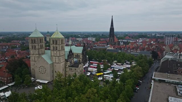 An aerial drone shot of St. Paulus Dom, also known as M&uuml;nster Cathedral, on Domplatz in M&uuml;nster on a sunny day. It is a central and culturally significant area of central M&uuml;nster, Germany. Busy Market