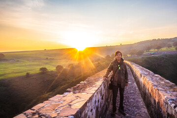 Man in aqueduct at dawn with sun behind, Tepotzotlán state of Mexico 