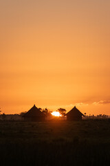 Sunset in the countryside with silhouette of wooden huts