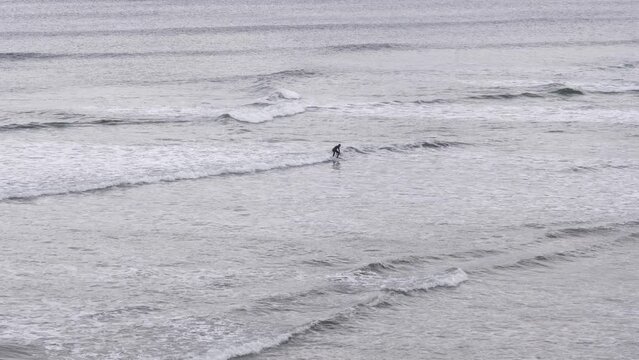 A surfer riding a wave in the Atlantic Ocean on a cold, choppy day. Tullan Strand, Bundoran, Co. Donegal, Ireland