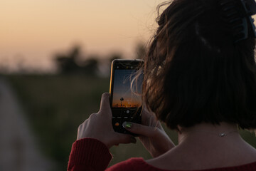 short-haired woman taking photos at sunset