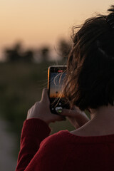 short-haired woman taking photos at sunset