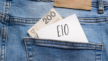 White card with a handwritten inscription "E10", put into the pocket of blue pants jeasnow, next to Polish banknotes PLN (selective focus)