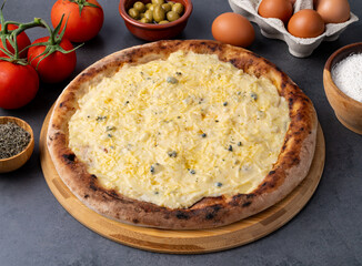 Four cheese style pizza over stone background with tomatoes, olives and oregano