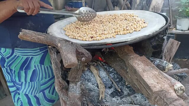 Latin woman cooking chickpeas on clay comal for food
