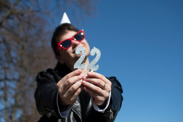 A woman in sunglasses and black leather jacket holding birthday numeral candle	