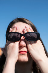 Conceptual portrait of a woman in sunglasses. Young attractive woman covering her face with a her hands	