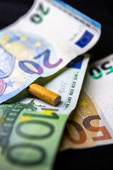 Discarded cigarette butt and euro banknotes - obrazy, fototapety, plakaty