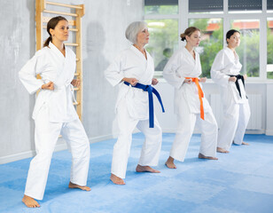 Women of different ages in kimono standing in fight stance during group karate training