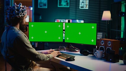Computer engineer using EEG headset, starting mind upload process using green screen PC. Man using...