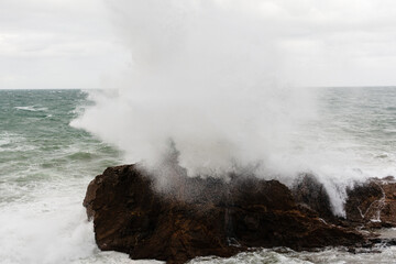 Sea waves crashing hard against a rock in winter.