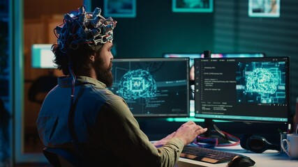 Man with EEG headset on writing code allowing him to transfer mind into computer virtual world,...