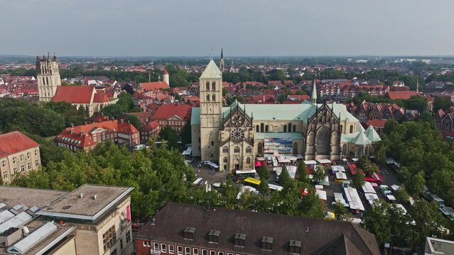 An aerial drone shot of St. Paulus Dom, also known as M&uuml;nster Cathedral, on Domplatz in M&uuml;nster on a sunny day. It is a central and culturally significant area of central M&uuml;nster, Germany. Busy Market