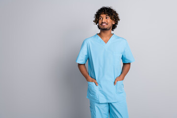 Photo of qualified doctor man hands in uniform pocket look empty space isolated grey color...
