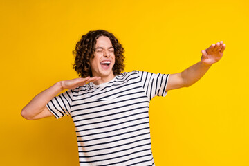 Photo of nice young man enjoy dancing wear striped t-shirt isolated on yellow color background