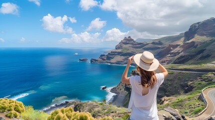 A tourist woman taking a photo from a viewpoint on the coast of the island of Gran Canaria. Spain.