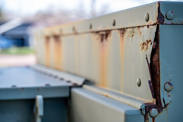 Rusted and peeling paint on an electrical transformer exposed to the elements. 