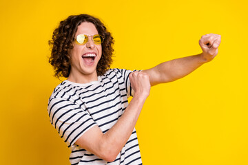 Photo of nice young man have fun dancing wear striped t-shirt isolated on yellow color background
