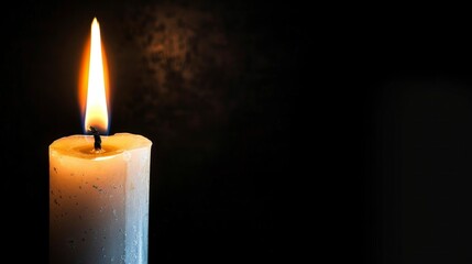 lit white candle on black background giving light in high resolution