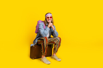 Full body portrait of cool young man sit valise empty space ad wear denim shirt isolated on yellow...