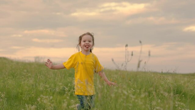 Child running through field of flowers at sunset. Happy family. Happy little girl dreams of flying in nature. Children fantasies. Happy child, girl runs raising her hands like flyer in green grass