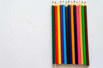 A Row Of Colored Pencils Are Lined Up On A White Table.
