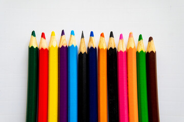 A Row Of Colored Pencils Are Lined Up On A White Table.
