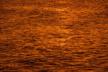 Golden light reflecting off a water wave at the sea and sand on sunset. Pure Gold Tone