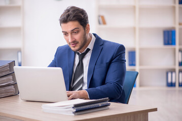Young male employee and too much work in the office