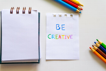 Notepad With the Words Be Creative Next to Colored Pencils