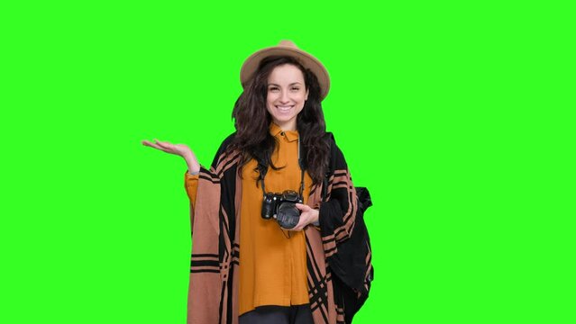 Happy female traveler holding camera, pointing copy space on the chroma key