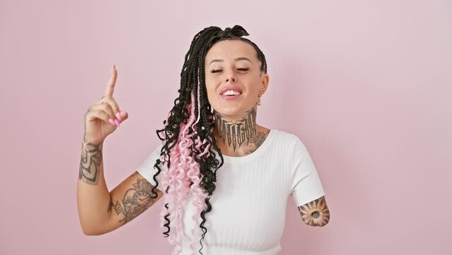 Hispanic amputee woman, overjoyed with surprise, pointing up confidently while standing isolated over pink background, mirroring astonishment, positivity and happiness with a radiant smile.