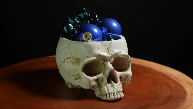 Gothic human skull with Christmas balls toys. Dark moody gothic Christmas celebration. Human head skull dark concept.
