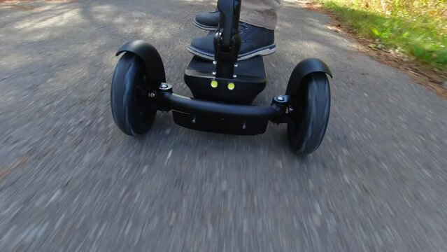 Person driving a motorized electric scooter his business and errands. Recreational electric ability vehicle footage movement from the front. Ecology, accessibility and convenience concept.