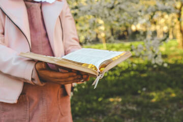 Girl with the Bible in her hands in the spring garden