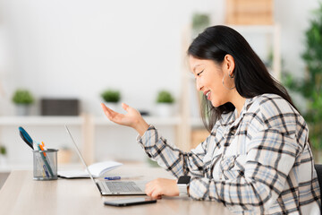 Side view of a young chinese woman talking during an online meeting from home