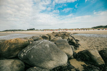 Stone groyne close-up on beach background.Stone boulders on the beach at low tide.Marine photo wallpaper.Nature of the North Sea coast. Frisian Islands of Germany. Rest on the sea. 
