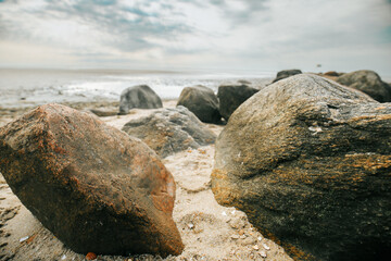 Stone boulders on the beach .Wadden Sea Coast.Stone groyne close-up on cloudy sky background.. Marine photo wallpaper.Nature of the North Sea coast. Frisian Islands of Germany. 