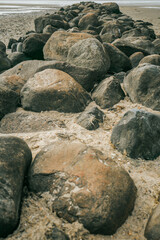 Stone groyne close-up on beach background.Stone boulders on the beach at low tide.Marine photo wallpaper.Nature of the North Sea coast. Frisian Islands of Germany.