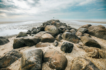 Fototapeta na wymiar Stone boulders on the beach at low tide.Marine photo wallpaper. Rest on the sea.