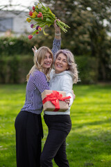 Mother and daughter smiling with gift and tulips.