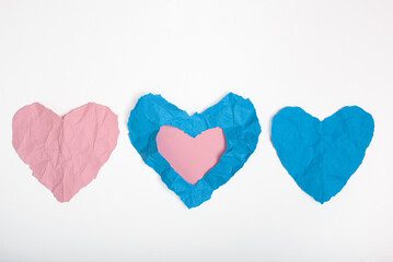 Blue and pink crumpled paper texture in the shape of hearts isolated on white background. Concept of love, heartbreak.