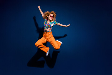 Full size photo of pretty young woman jump empty space ad wear top isolated on dark blue color background