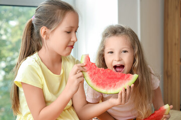 Happy little girls eating fresh watermelon in kitchen