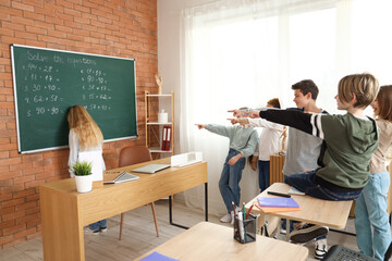 Little children bullying their classmate during lesson at school - obrazy, fototapety, plakaty