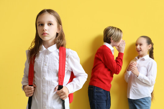 Bullied little girl and her classmates on yellow background