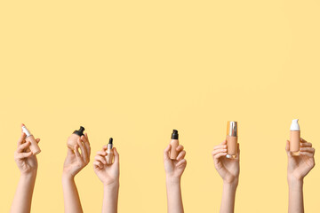 Female hands with foundations and highlighter on yellow background