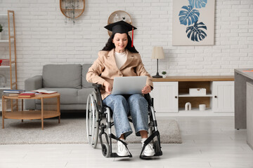 Beautiful female graduate student in wheelchair with graduation cap and modern laptop at home