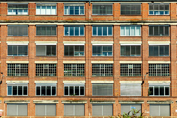 facade of old brick factors building with different windows and shutter blinds,